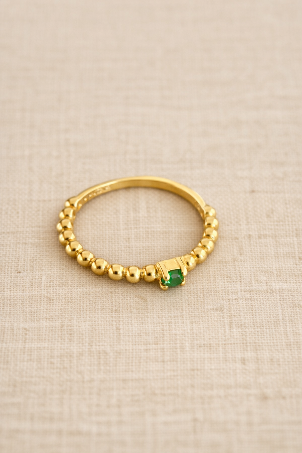 Beaded Ring with Green Zirconia on beige fabric
