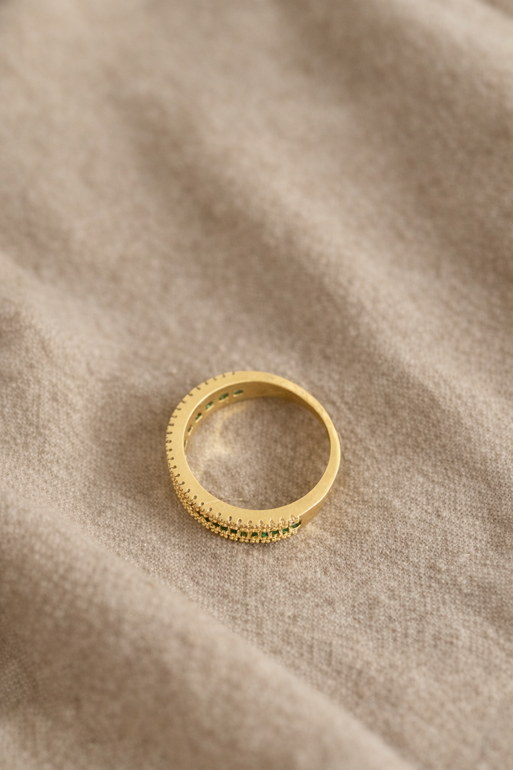 18K gold plated ring with green zirconia on fabric background