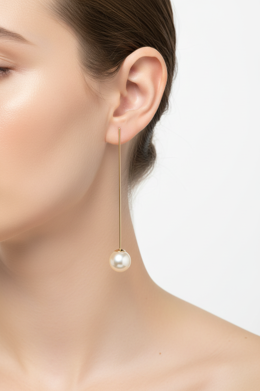 Gold long pearl drop earring worn on model's ear