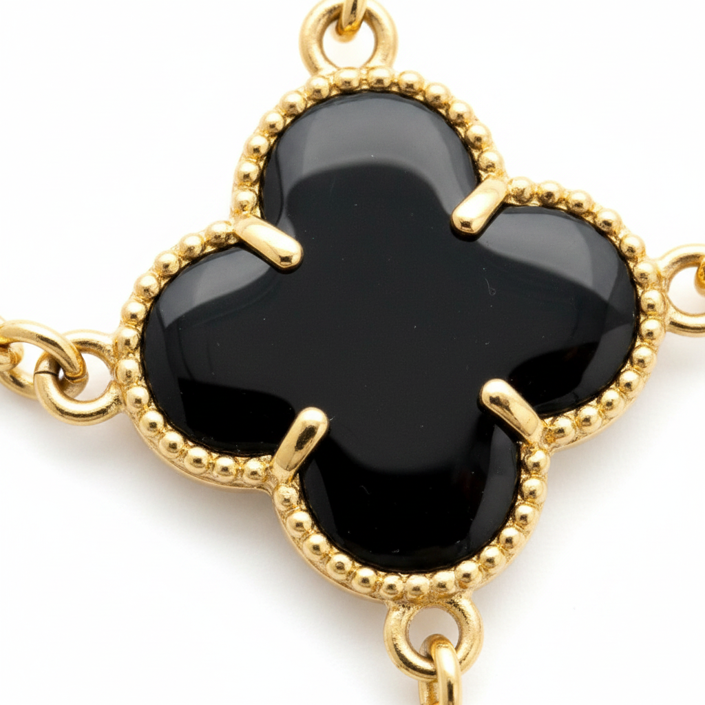 Close-up of gold Portuguese link chain with black clover pendants